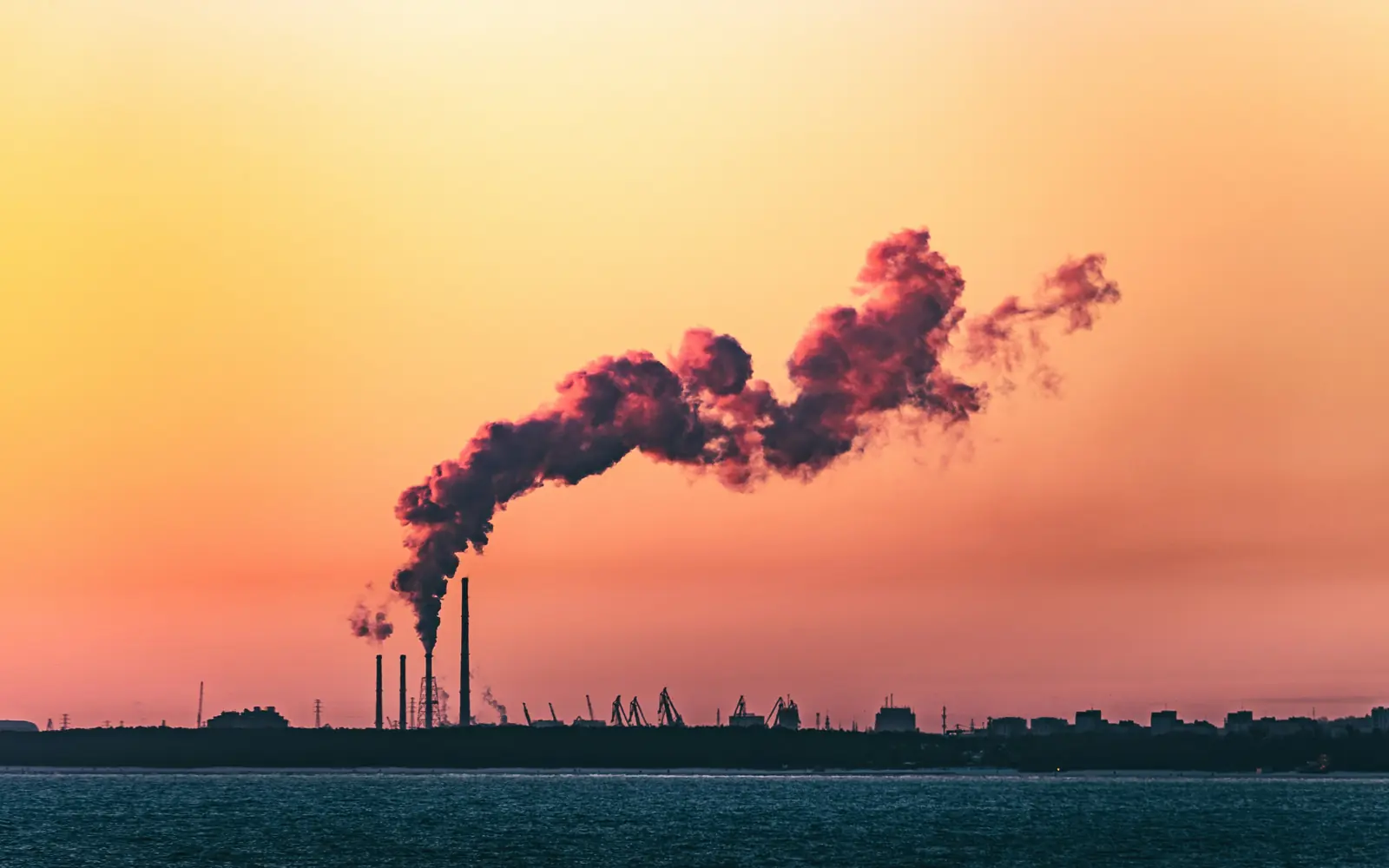 Industrial emissions plume against a sunset sky